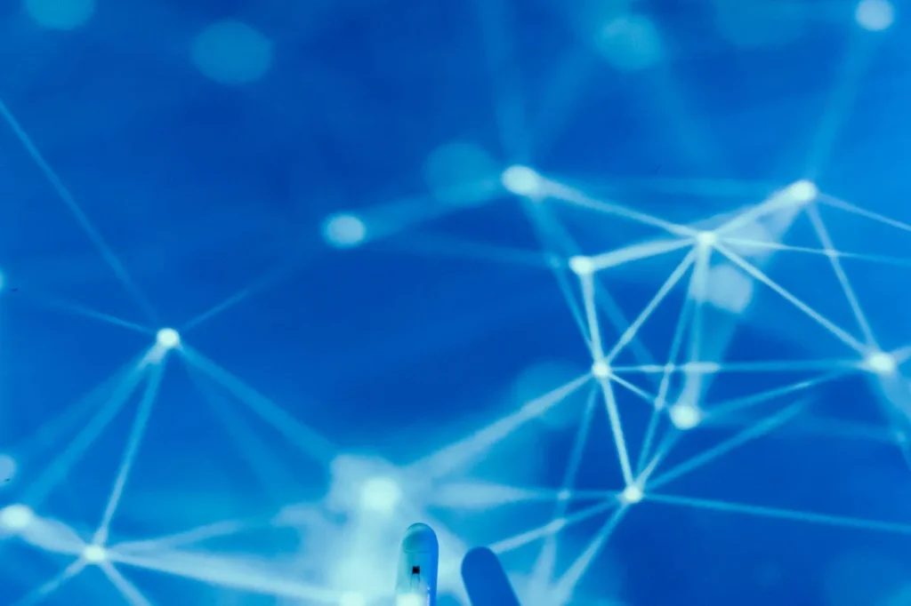Main robotique touchant un réseau numérique sur fond bleu, symbole de l'intelligence artificielle