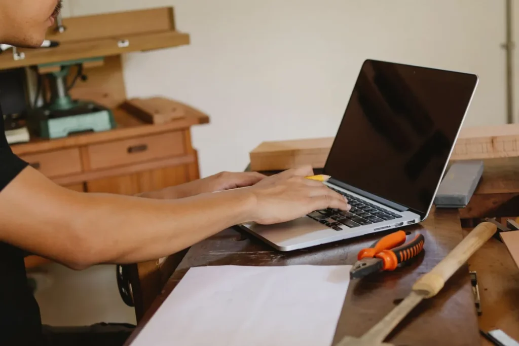 Artisan travaillant sur un ordinateur portable dans son atelier de menuiserie
